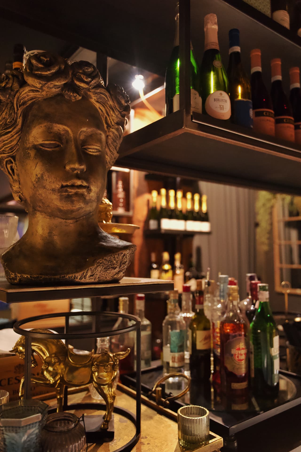 Busto classico dorato e statuetta al bar